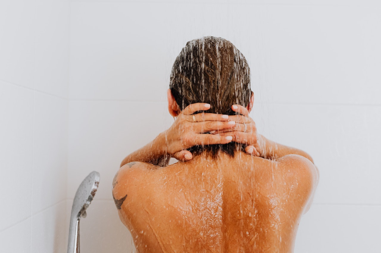 Mujer de espalda duchándose