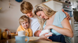 Young parents with newborn baby and small toddler son at home.