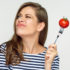 Woman holding tomato on fork looking up.