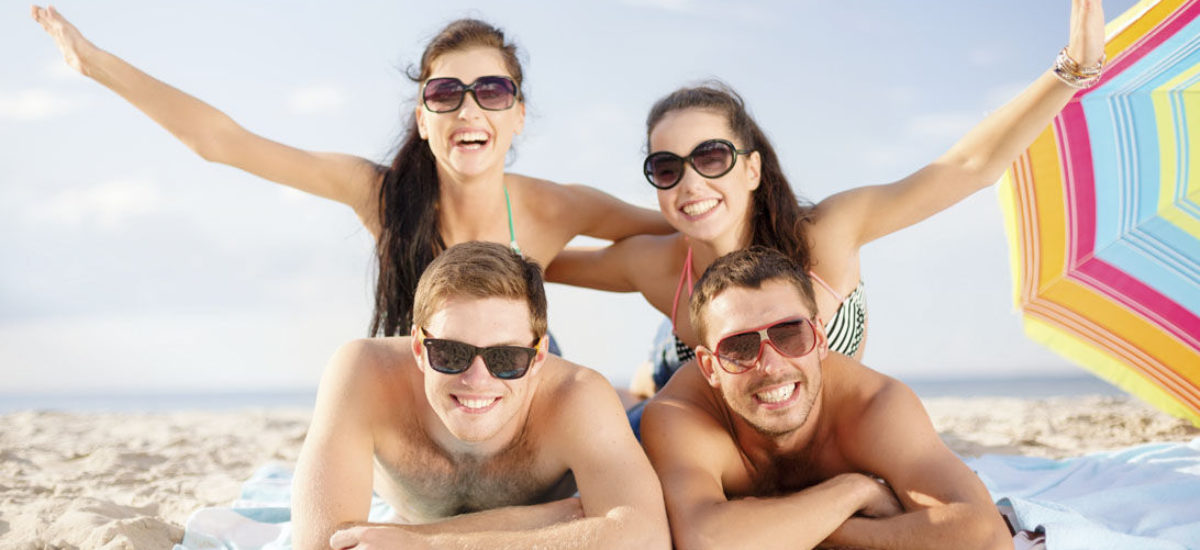 group of smiling people having fun on the beach
